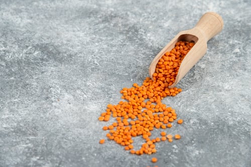 Preview: Wooden spoon of red raw lentils on marble background