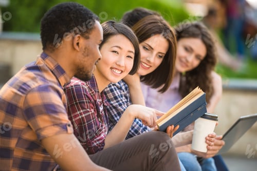 Preview: Smiling Young People Enjoying Reading a Book Outdoors
