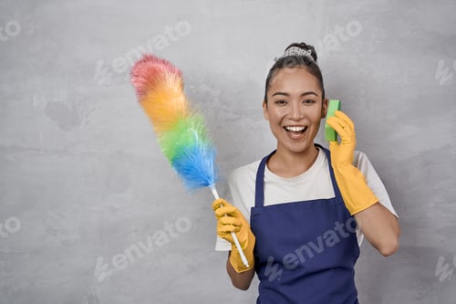 Preview: Playful young woman in uniform holding colorful microfiber duster