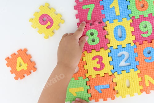 Preview: Little girl playing with colorful puzzles at white table, top view. Educational toy