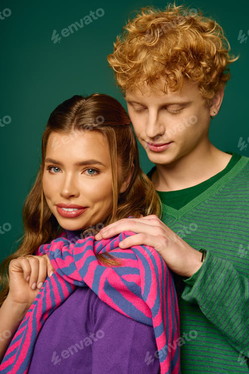Preview: Young couple sharing an intimate moment in stylish attire against a vibrant backdrop
