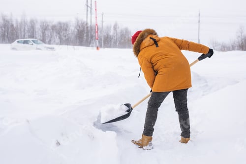 Preview: Man removing snow and ice from the sidewalk in front of house. Winter season