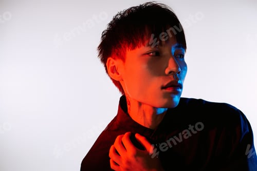 Preview: Handsome stylish young man poses dramatically against a vibrant backdrop in modern fashion setting