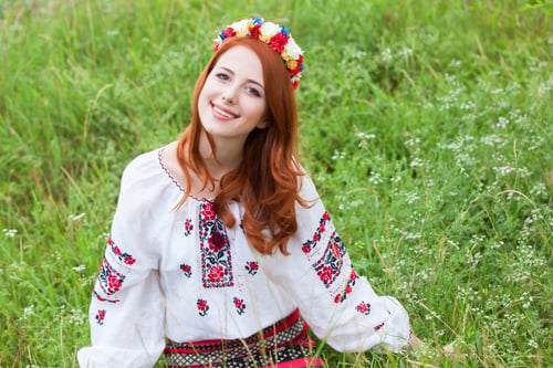 Preview: Redhead girl in nationac ukrainian clothes on the green grass.