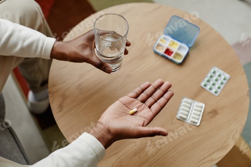 Preview: Top view unrecognizable man holding capsule pill in hand