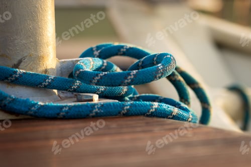 Preview: Securely Fastened Blue Rope Wrapped Around Metal Bollard on Wooden Dock