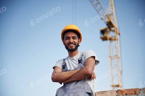 Preview: Standing with arms crossed. Handsome Indian man is on the construction site