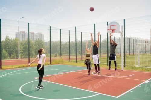 Preview: Team of young intercultural friends or students working out on basketball court