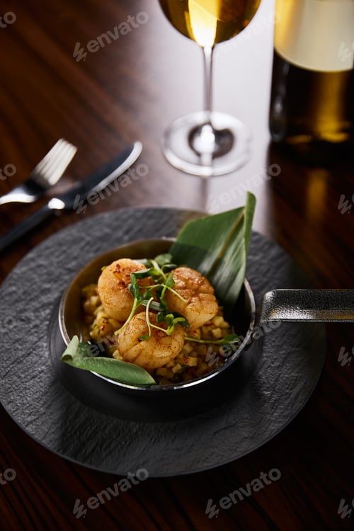 Preview: delicious grilled scallops served with cutlery and white wine on wooden table