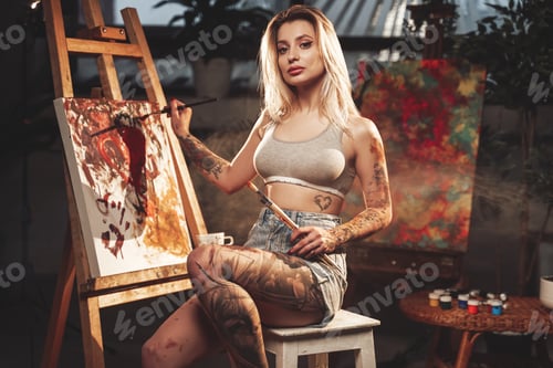 Preview: Seductive woman painting canvas in dark and atmospheric room