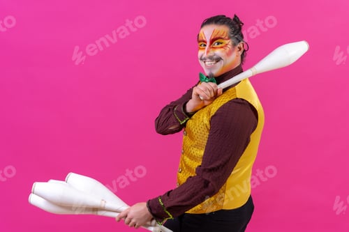 Preview: Funny circus performer holding clubs on his shoulder isolated on pink background