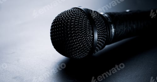 Preview: Close up of black microphone on a black background.