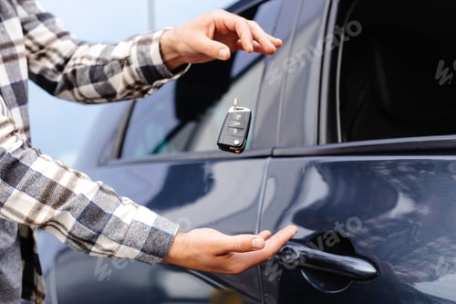 Preview: Guy holding key in hand and smiling at camera. Man showing key from his new electric car