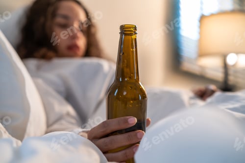 Preview: Drunk Latino woman hold beer bottle, and crying feel hangover on bed at night