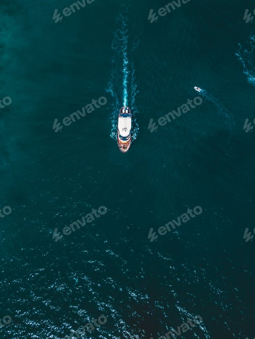 Preview: Aerial view of a white and brown boat sailing on the water with other small boats.