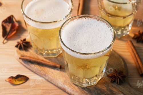 Preview: Spiced apple cider sparkles in faceted glasses with cinnamon and star anise on wooden board