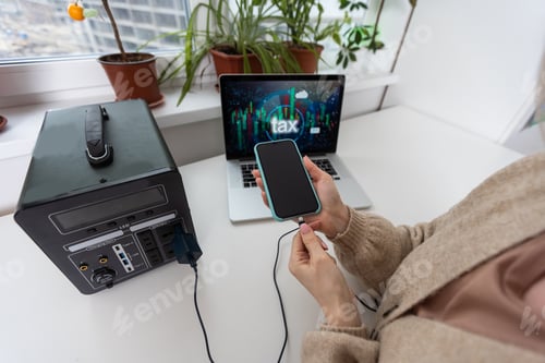 Preview: Young woman with portable power station at table in office.