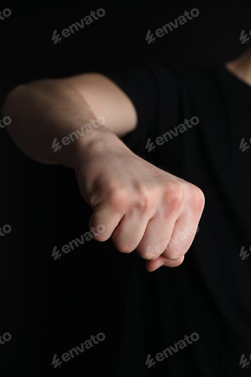 Preview: Man showing fist with space for tattoo on black background, closeup