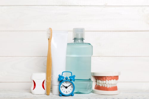 Preview: Mouthwash and other oral hygiene products on colored table top view with copy space