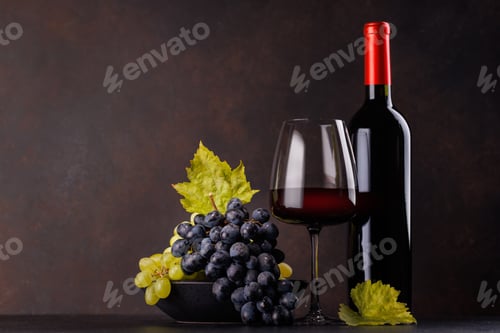 Preview: Red wine bottle with a glass and basket of fresh grapes
