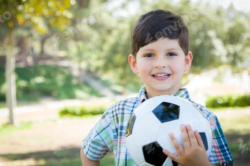 Preview: Cute Young Boy Playing with Soccer Ball Outdoors in the Park.