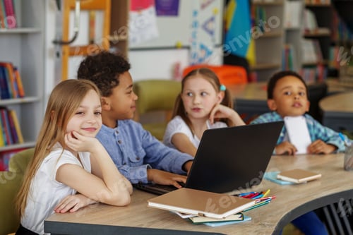 Preview: Multiracial group of children sitting in row at school classroom and using laptops. Back to school.