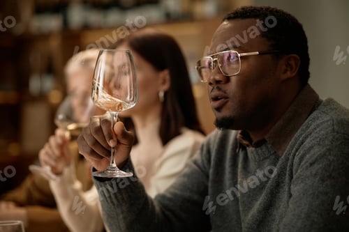 Preview: Middle Aged Black Man Evaluating Wine during Tasting with Diverse Group