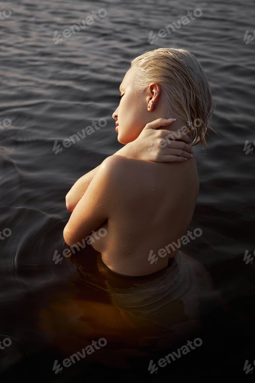 Preview: Nude naked sexy woman in water at sunset. Beautiful blonde woman with short wet hair, art portrait