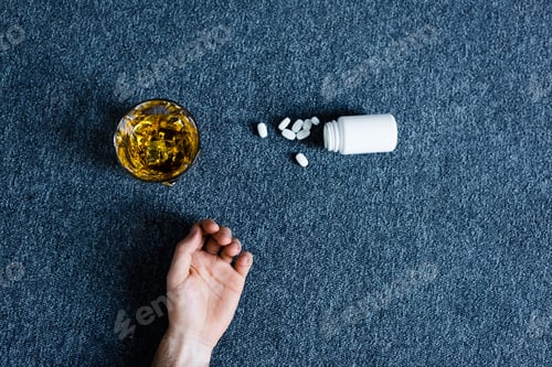 Preview: top view of male hand near container with pills near glass of whiskey and container with pills