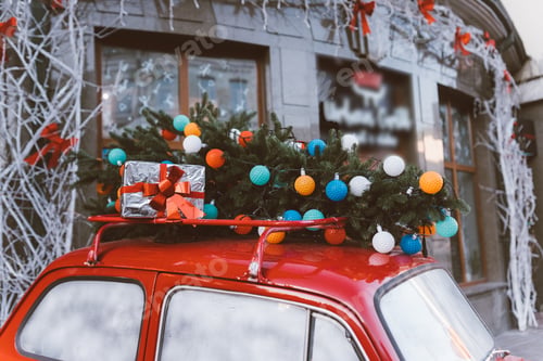 Preview: Red retro car with a Christmas tree fir tied to the roof