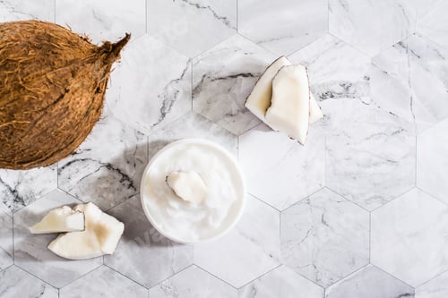 Preview: A piece of coconut in coconut oil in a jar and coconut. Natural cosmetic. Top view
