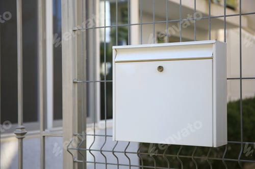 Preview: White metal letter box on fence outdoors
