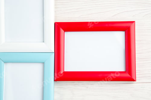 Preview: Overhead view of three empty picture frames in different colors on stripped background