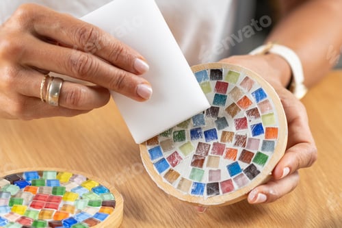 Preview: Woman completing coaster surface by adding a fixator finish in a home studio.