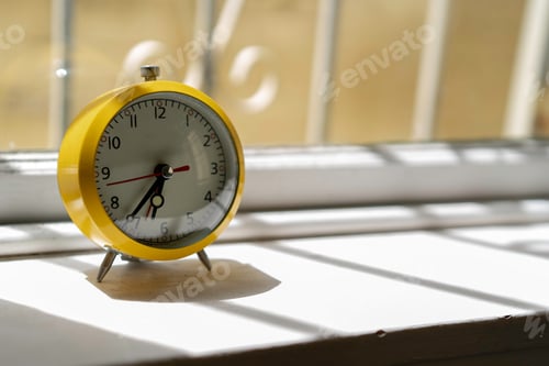 Preview: Yellow retro clock at 6:37am on windowsill with natural light coming in from the window