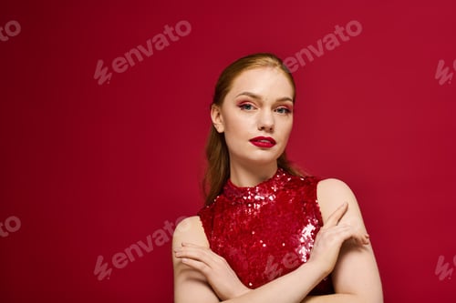 Preview: Young woman in a red sequined dress poses confidently against a vibrant pink background