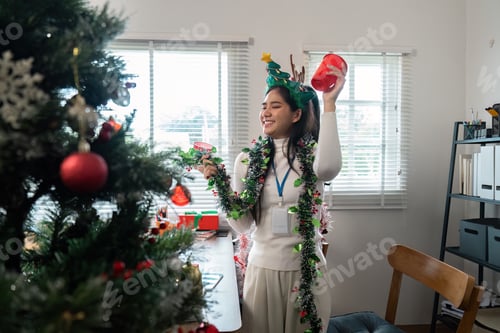 Preview: Festive Young Woman Decorating Christmas Tree with Ornaments and Holiday Cheer in Bright Living Room