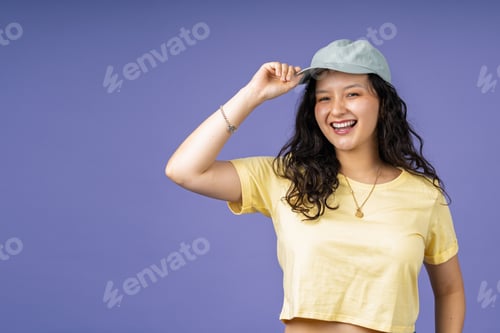 Preview: Young woman smiling while adjusting baseball cap