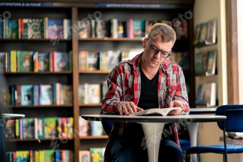 Preview: professor sits in a scientific and technical library reads a book and prepares write a dissertation