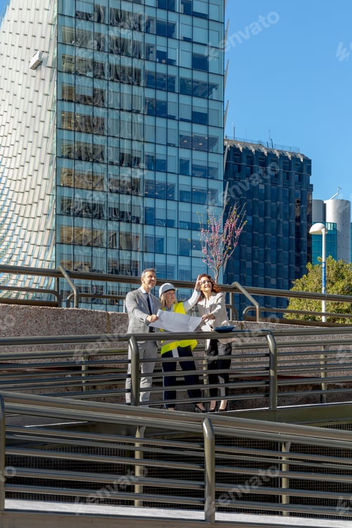 Preview: Professionals examining blueprints in front of a modern office building