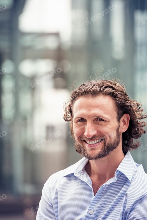 Preview: A man with curly hair and a beard on a city street.