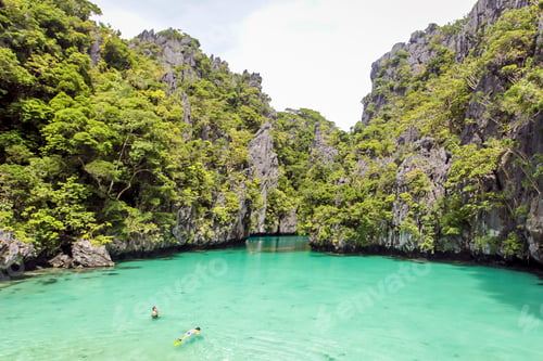 Preview: Tourists floating in a serene turquoise lagoon surrounded by lush cliffs