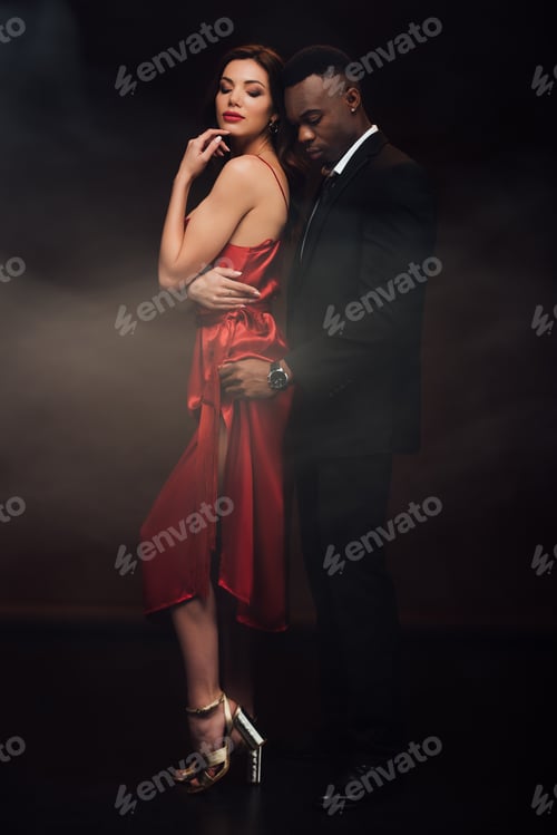 Preview: african american man embracing beautiful woman in red dress on black with smoke