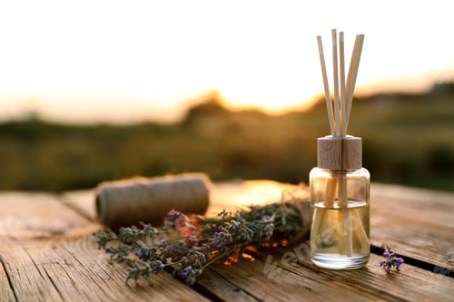 Preview: Reed air freshener and fresh lavender flowers on wooden table in field. Space for text