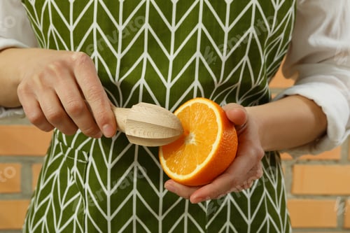 Preview: Woman hold juicer and orange against brick wall background