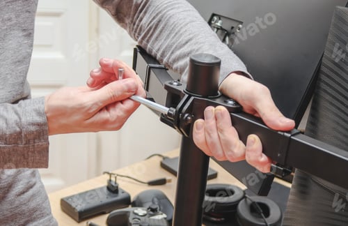 Preview: The hands of a young caucasian guy without a face twists a nut on a bracket with a wrench.