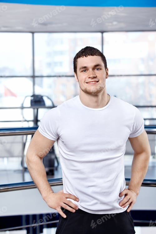 Smiling Man in Gym Setting Wearing White Shirt