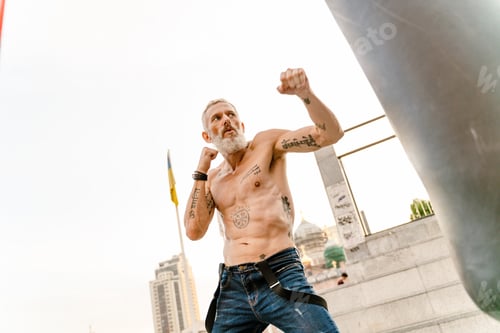 Preview: Shirtless mature man with tattoo boxing working out on sports ground
