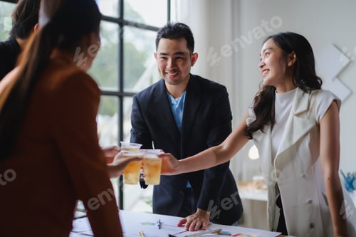 Preview: Business team celebrating success with drinks in office