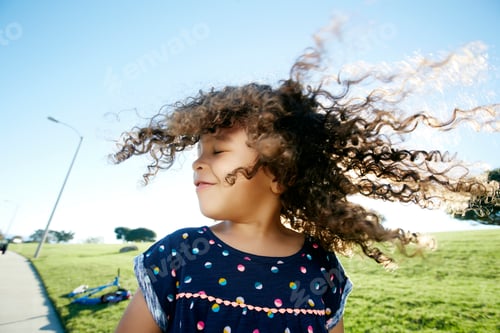 Preview: Young mixed race girl aged 4 outdoors, curly hair fanning out